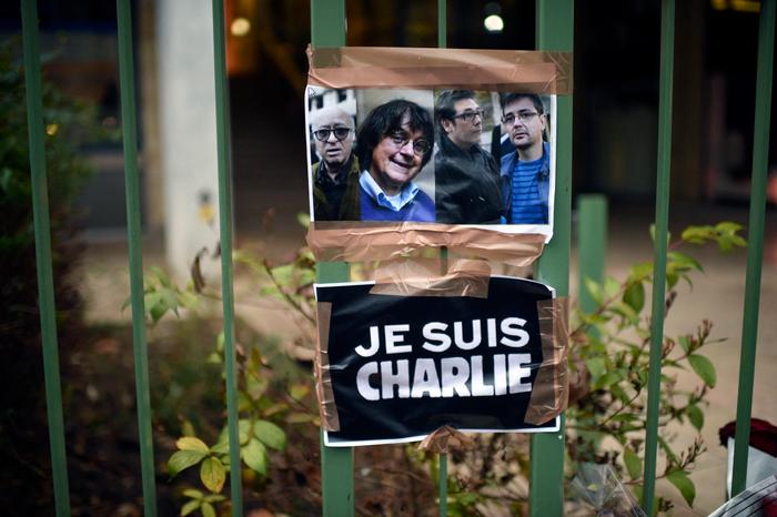 Un panneau indiquant « Je suis Charlie » est placé à côté des portraits des dessinateurs français Georges Wolinski, Jean Cabut (alias Cabu), Bernard Verlhac (alias Tignous) et du rédacteur en chef de Charlie Hebdo Stéphane Charbonnier (alias Charb) près des bureaux du journal satirique français Charlie Hebdo à Paris le 8 janvier 2015, à la suite d'une attaque contre les bureaux du journal le 7 janvier par des hommes armés qui a fait 12 morts, dont Wolinski, Cabu, Tignous et Charb.