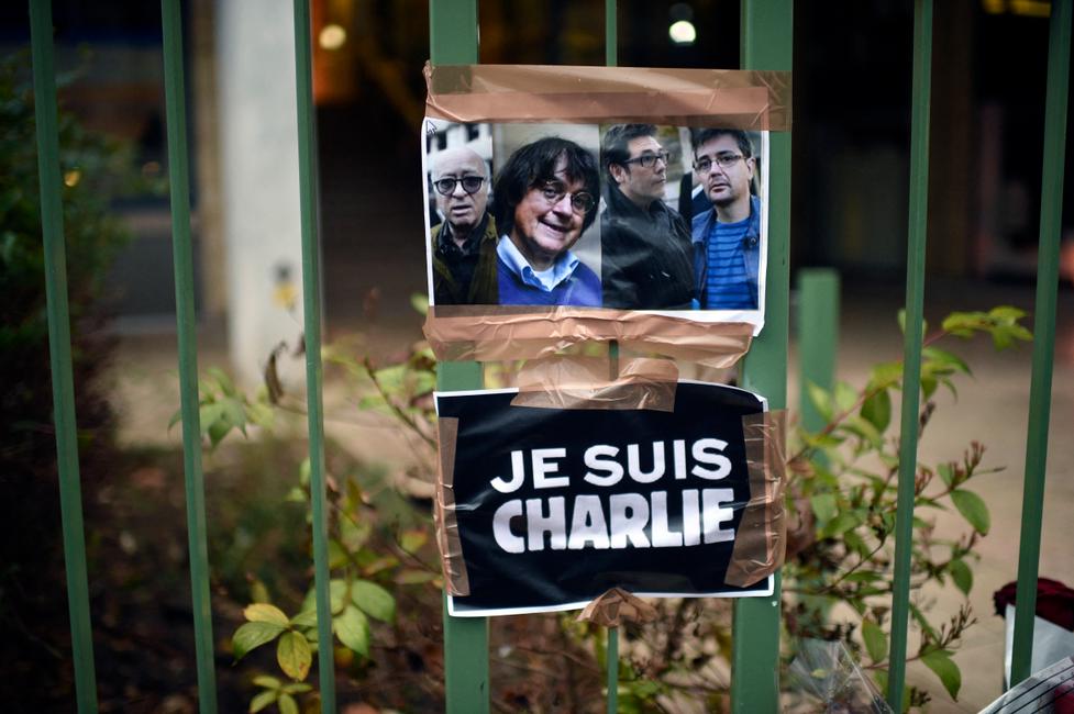 Un panneau indiquant « Je suis Charlie » est placé à côté des portraits des dessinateurs français Georges Wolinski, Jean Cabut (alias Cabu), Bernard Verlhac (alias Tignous) et du rédacteur en chef de Charlie Hebdo Stéphane Charbonnier (alias Charb) près des bureaux du journal satirique français Charlie Hebdo à Paris le 8 janvier 2015, à la suite d'une attaque contre les bureaux du journal le 7 janvier par des hommes armés qui a fait 12 morts, dont Wolinski, Cabu, Tignous et Charb.