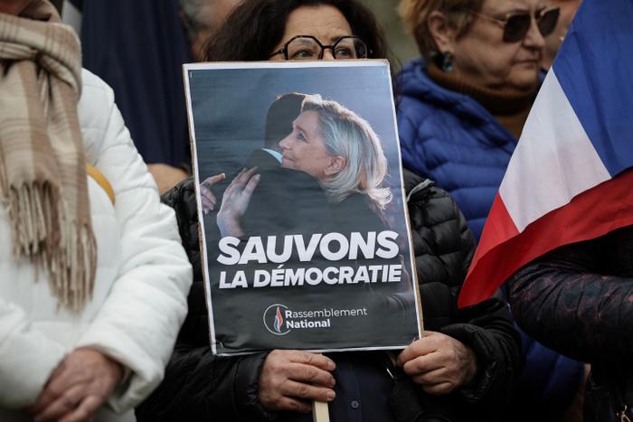 Une femme brandit une pancarte « Sauvons la démocratie » lors d'un rassemblement de soutien à Marine Le Pen, après sa condamnation pour un système de faux emplois au Parlement européen, à Saint-Orens-de-Gameville, près de Toulouse, le 5 avril 2025.