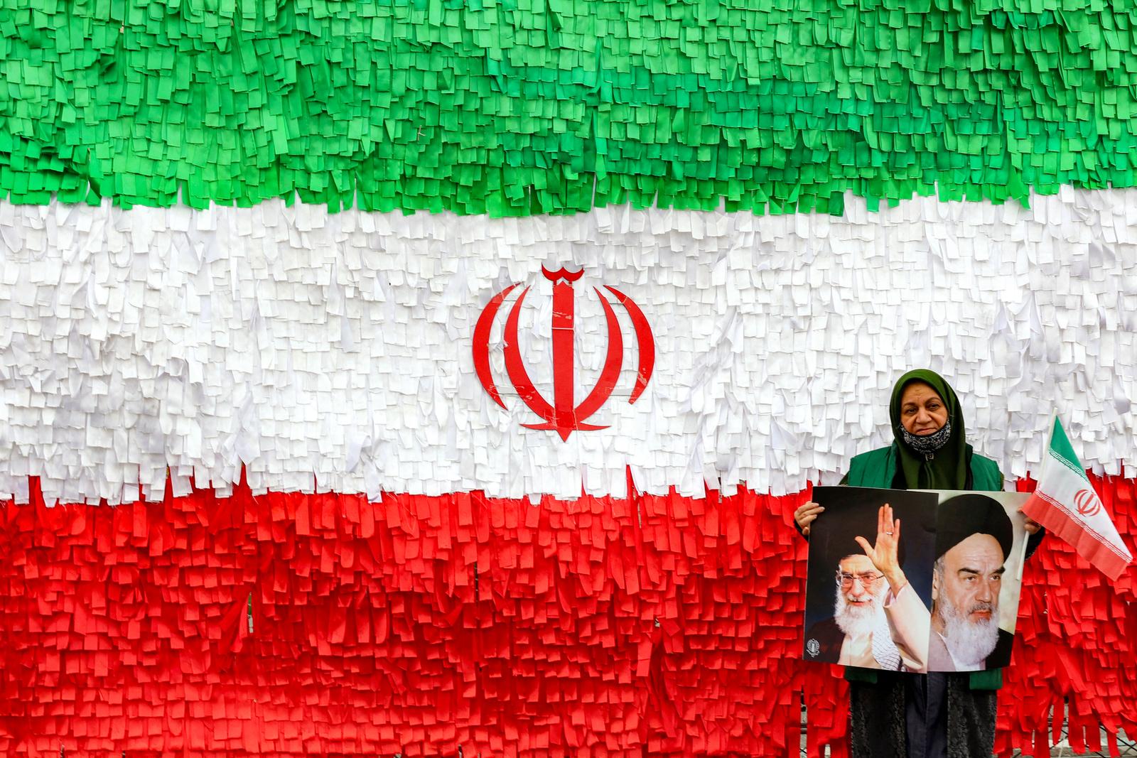 Une femme pose avec les portraits des anciens et actuel guides suprêmes de l’Iran, l’ayatollah Ruhollah Khomeini et l’ayatollah Ali Khamenei, devant une installation représentant le drapeau iranien, lors d’un rassemblement marquant le 47e anniversaire de la révolution islamique de 1979, à Téhéran, le 11 février 2026. (Image d'illustration)