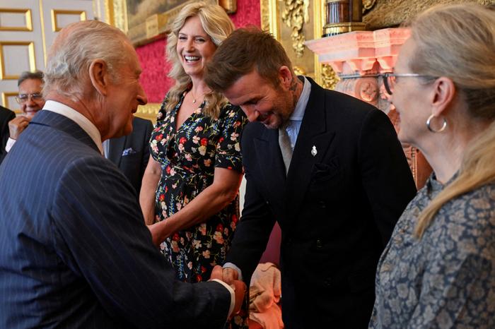 L’ancien footballeur anglais David Beckham (au centre) serre la main du roi Charles III (devant à gauche) lors de la cérémonie des King's Foundation Awards, organisée à l’occasion du 35e anniversaire de la King’s Foundation, au palais St James, à Londres, le 12 juin 2025.