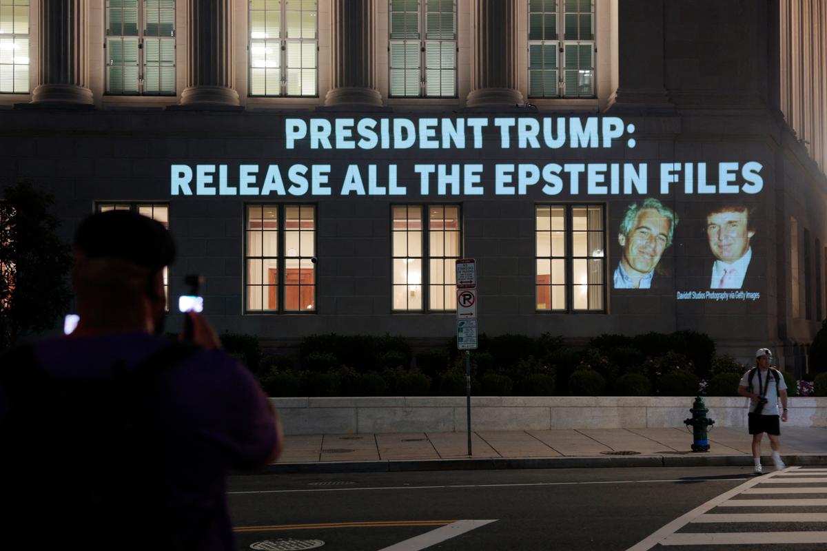 Des personnes prennent en photo une image du président américain Donald Trump et de Jeffrey Epstein, projetée sur le siège du ministère américain du Commerce, le 18 juillet 2025, à Washington.