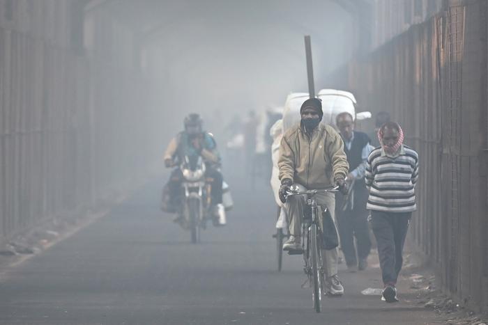 Des voyageurs traversent un pont par une matinée d'hiver brumeuse à New Delhi, le 19 décembre 2024.