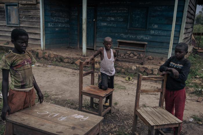 Des jeunes garçons déplacent des meubles d'une école utilisée par les combattants du Mouvement du 23 mars (M23) comme base militaire à Kishishe, dans l'est de la République démocratique du Congo, le 5 avril 2023.