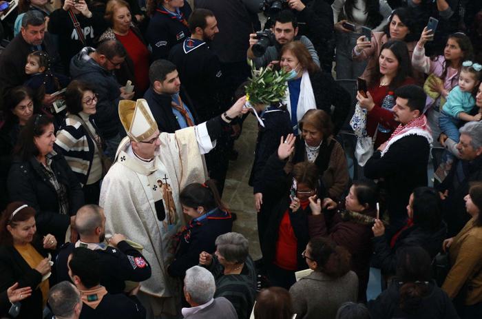 Pierbattista Pizzaballa, patriarche latin de Jérusalem, asperge d'eau bénite les pèlerins catholiques assistant à une messe en l'église du Baptême du Christ, près du lieu du baptême d'Al-Maghtas, où, selon les chrétiens, Jésus aurait été baptisé par saint Jean, dans la vallée du Jourdain, à environ 60 km au sud-ouest d'Amman, la capitale jordanienne, le 13 janvier 2023.