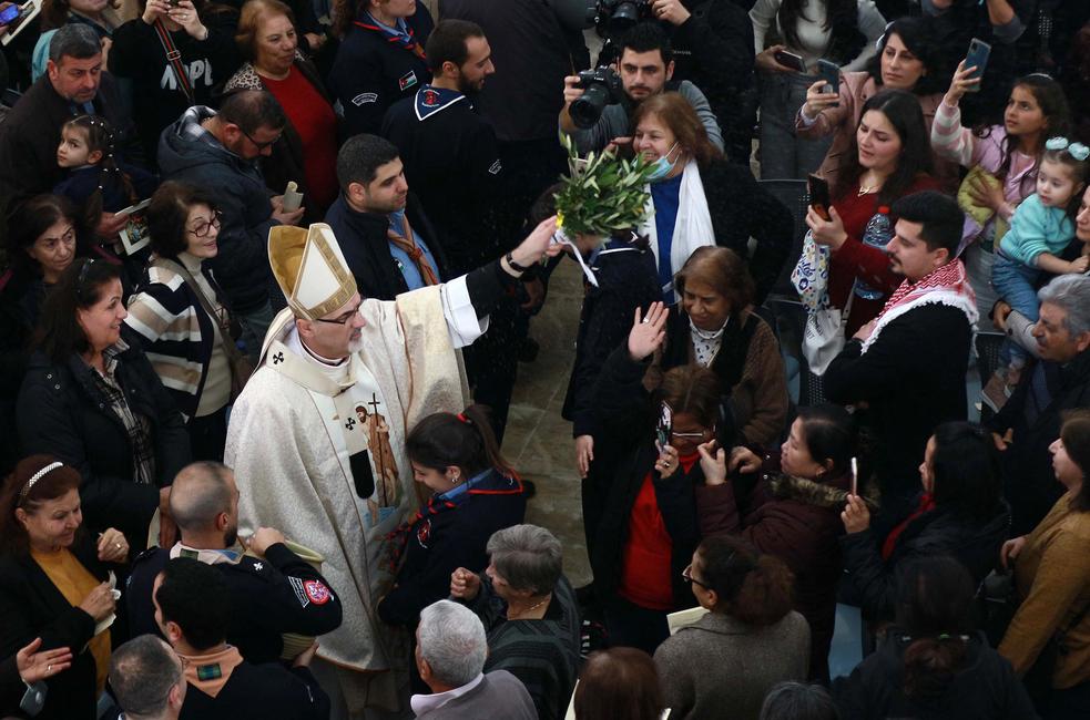 Pierbattista Pizzaballa, patriarche latin de Jérusalem, asperge d'eau bénite les pèlerins catholiques assistant à une messe en l'église du Baptême du Christ, près du lieu du baptême d'Al-Maghtas, où, selon les chrétiens, Jésus aurait été baptisé par saint Jean, dans la vallée du Jourdain, à environ 60 km au sud-ouest d'Amman, la capitale jordanienne, le 13 janvier 2023.