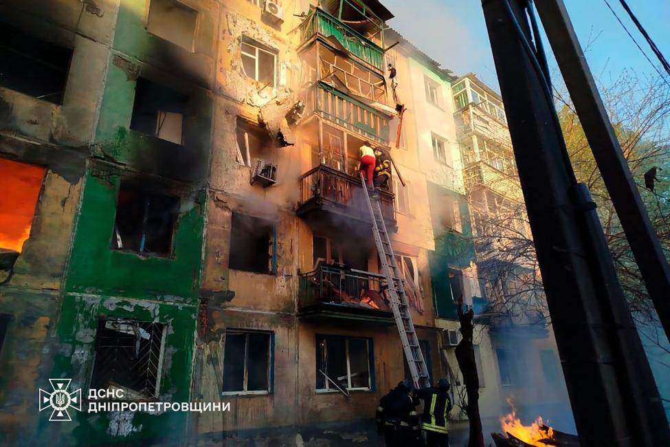 Sur cette photographie prise et publiée par les services d'urgence ukrainiens le 25 avril 2025, des sauveteurs ukrainiens évacuent une femme d'un immeuble résidentiel en feu à la suite d'une attaque de drone à Pavlograd, dans la région de Dnipropetrovsk.