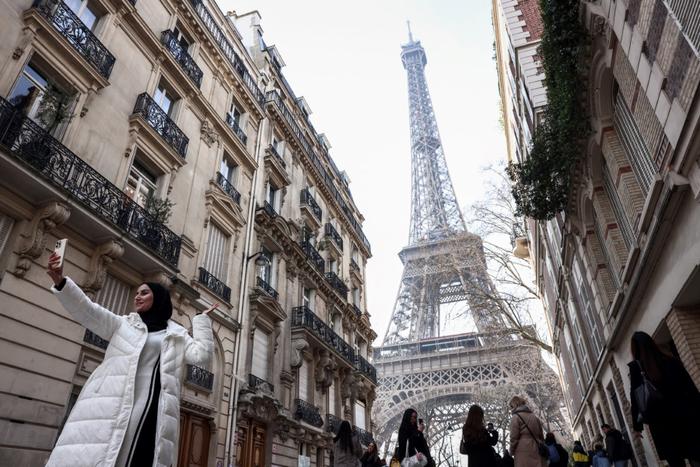 Un touriste prend un selfie devant la Tour Eiffel à Paris, le 19 février 2025.