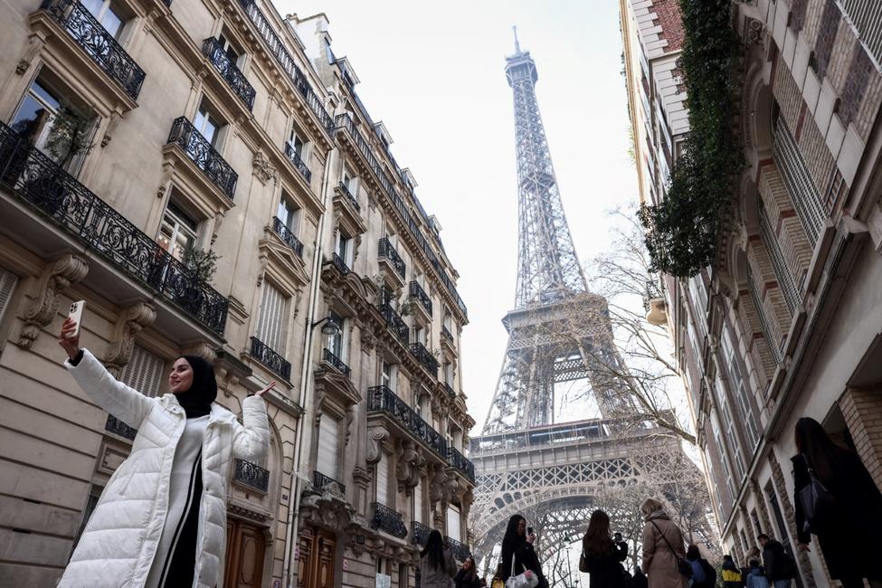 Un touriste prend un selfie devant la Tour Eiffel à Paris, le 19 février 2025.