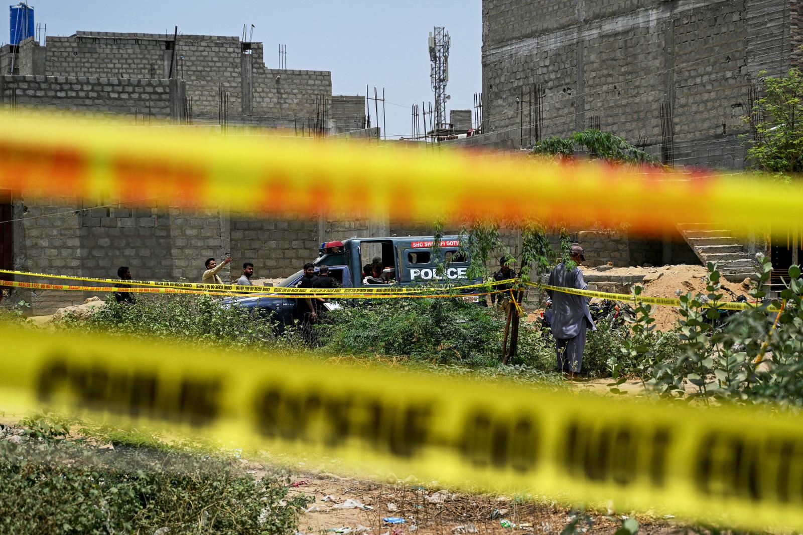 Des habitants se rassemblent tandis que des membres des forces de l'ordre inspectent un site bouclé par des rubans de sécurité après qu'un drone présumé a été abattu à Karachi, le 8 mai 2025. L'armée pakistanaise a déclaré, ce même jour, avoir abattu 25 drones indiens, au lendemain des violences les plus graves entre les deux puissances nucléaires depuis vingt ans.