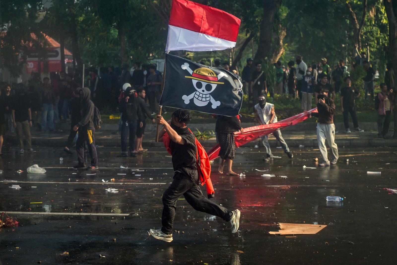 Un manifestant porte le drapeau national indonésien et un drapeau pirate de l'anime japonais « One Piece », lors d'une manifestation à Surabaya, en Indonésie, le 29 août 2025.
