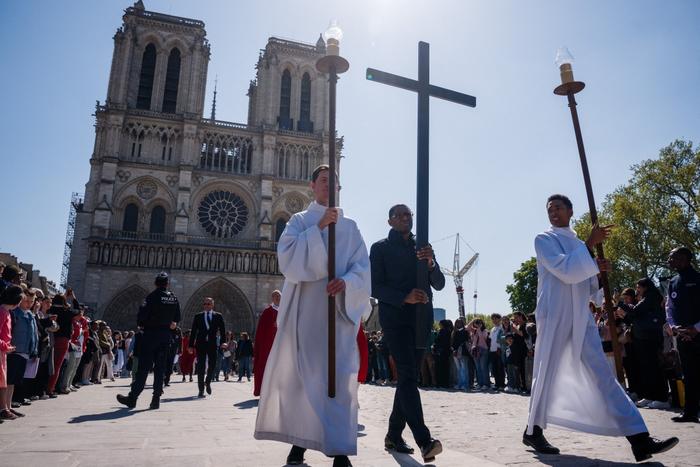 Un prêtre porte une croix lors d'une procession du Chemin de Croix, qui rappelle la dernière étape du voyage de Jésus, devant la cathédrale Notre-Dame de Paris, dans le cadre des célébrations du Vendredi Saint, à Paris, le 18 avril 2025.
