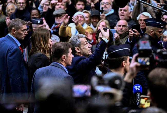 L'ancien président Nicolas Sarkozy salue la foule de Français venus le soutenir avant qu'il se présente à la prison de La Santé.