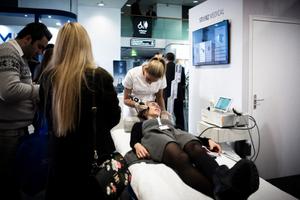 Une femme essaie un appareil d'onde de choc dans un stand du Congrès sur la science esthétique, la chirurgie plastique et la dermatologie cosmétique (IMCAS) à Paris le 1er février 2018.