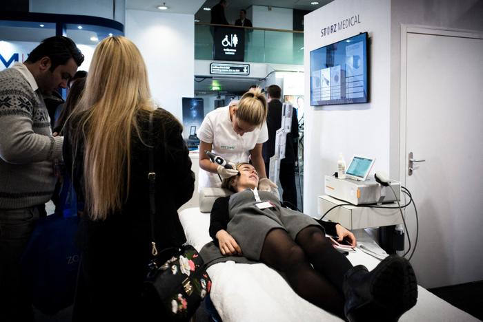 Une femme essaie un appareil d'onde de choc dans un stand du Congrès sur la science esthétique, la chirurgie plastique et la dermatologie cosmétique (IMCAS) à Paris le 1er février 2018.