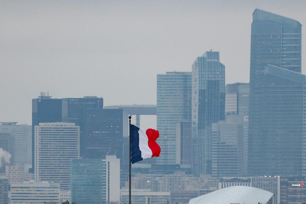 Cette photographie montre un drapeau français flottant au vent, avec la silhouette du quartier d'affaires de La Défense en arrière-plan, à Paris, le 5 décembre 2025.