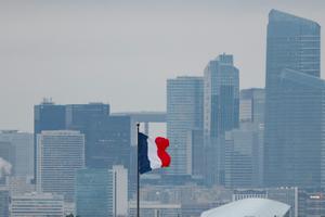 Cette photographie montre un drapeau français flottant au vent, avec la silhouette du quartier d'affaires de La Défense en arrière-plan, à Paris, le 5 décembre 2025.
