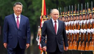 Sur cette photo de groupe diffusée par l'agence d'État russe Sputnik, le président russe Vladimir Poutine et le président chinois Xi Jinping inspectent une garde d'honneur lors d'une cérémonie de bienvenue au Grand Palais du Peuple à Pékin, le 20 mai 2026.