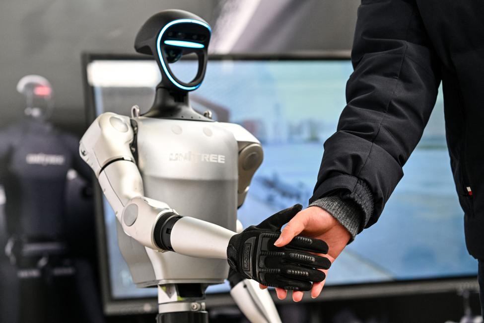Un homme serre la main d'un robot humanoïde d'Unitree Robotics lors de la Global Developer Conference, organisée par la Shanghai AI Industry Association, à Shanghai, le 21 février 2025. (Photo par Hector RETAMAL / AFP)