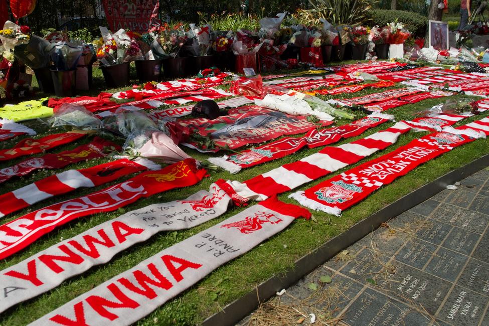 Des écharpes de Liverpool sont déposées aux côtés de fleurs devant un mémorial érigé près du stade d’Anfield à la mémoire de l’attaquant portugais Diogo Jota, à Liverpool, dans le nord-ouest de l’Angleterre, le 3 juillet 2025. L’attaquant de Liverpool Diogo Jota est mort, ainsi que son frère, tôt le 3 juillet 2025, dans un accident de la route survenu dans le nord-ouest de l’Espagne.