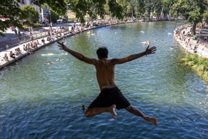 Un jeune homme plonge d'un pont dans le canal Saint-Martin alors que la France est touchée par une vague de chaleur, à Paris, le 12 juillet 2026.