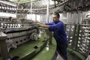Un technicien de la société Chamtex (production de tissus) amorce les bobines d'une tricoteuse, le 26 avril 2005 à Bobigny.