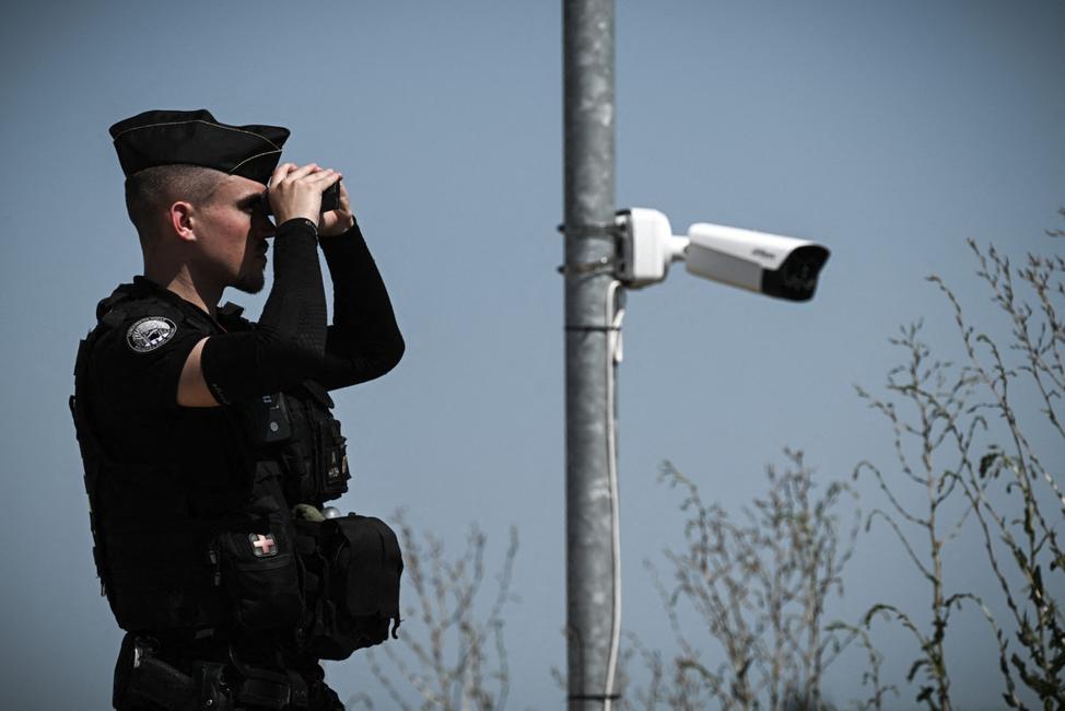 Un gendarme utilise des jumelles à côté de caméras de vidéosurveillance alors qu'il monte la garde sur les berges d'un chantier de construction de réservoir d'eau, la veille d'une manifestation prévue contre les « méga-bassins » à Sainte-Soline, dans le centre-ouest de la France, le 18 juillet 2024.