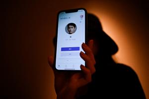 Une jeune femme montre sur son téléphone portable, à Pékin, son petit ami virtuel - un chatbot créé par XiaoIce, un système d'intelligence artificielle de pointe conçu pour tisser des liens émotionnels avec son utilisateur.