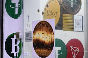 Les symboles du bitcoin et du stablecoin Tether (USDT) sont exposés dans une boutique de cryptomonnaies à Hong Kong, le 29 juillet 2025.