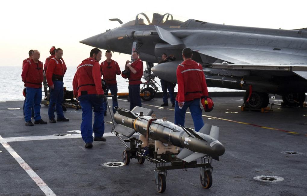 Des ingénieurs de la marine française installent un missile sur un avion de chasse Rafale à bord du porte-avions Charles-de-Gaulle, le 23 novembre 2015, dans le cadre de l'opération Chammal en Syrie et en Irak contre le groupe État islamique.