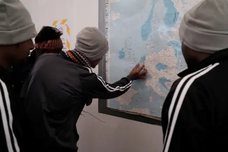 Des migrants du Bangladesh regardent une carte de l'Europe à bord du navire de sauvetage Ocean Viking de l'organisation humanitaire maritime européenne "SOS Méditerranée" après une opération de sauvetage au large de Malte, le 22 mai 2024.