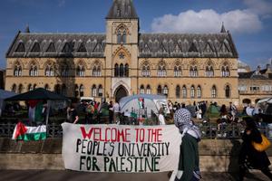 Le 7 mai 2024, à Oxford, dans l'Est de l'Angleterre, un homme portant un keffieh longe une banderole proclamant « Bienvenue à l'université du peuple pour la Palestine », alors qu'un campement pro-palestinien a été installé sur le campus de l'université.