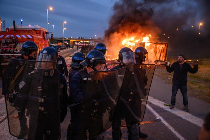 Des policiers français montent la garde près d'un camion en feu lors d'une manifestation d'agriculteurs à Narbonne, le 26 janvier 2024.