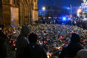 Des personnes en deuil entourent un mémorial de fortune composé de fleurs et de bougies en hommage aux victimes d'un attentat à la voiture piégée sur un marché de Noël à Magdebourg, dans l'est de l'Allemagne, le 23 décembre 2024.