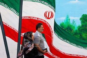 Un homme et une femme passent devant une fresque représentant des drapeaux nationaux iraniens dans une rue de Téhéran, le 20 août 2024. (Image d'illustration)