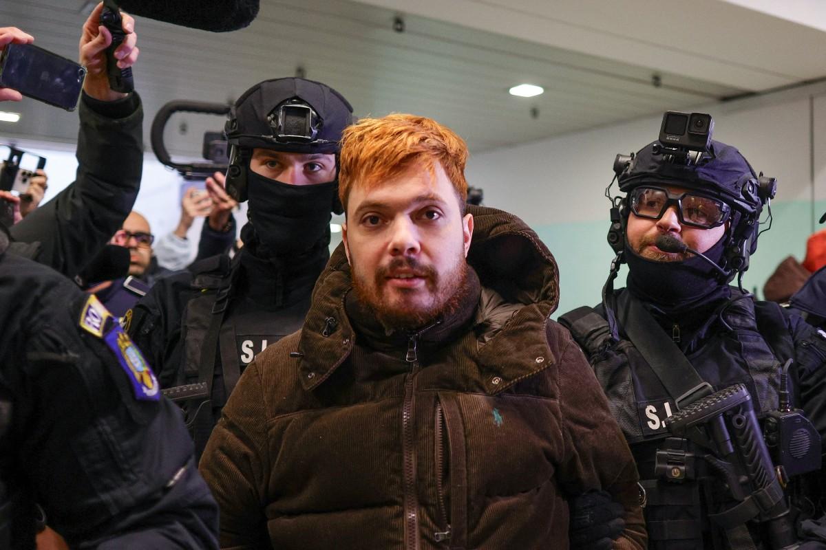 Mohamed Amra est escorté par des policiers à l'aéroport international Henri Coanda d'Otopeni près de Bucarest, en Roumanie, le 25 février 2025