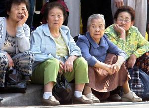 Des femmes âgées sud-coréennes assises sur un trottoir, attendant l'arrivée de Park Geun-hye, cheffe du Grand Parti national (GNP), principal parti d'opposition, lors de sa campagne pour les élections législatives à Séoul, en avril 2004.