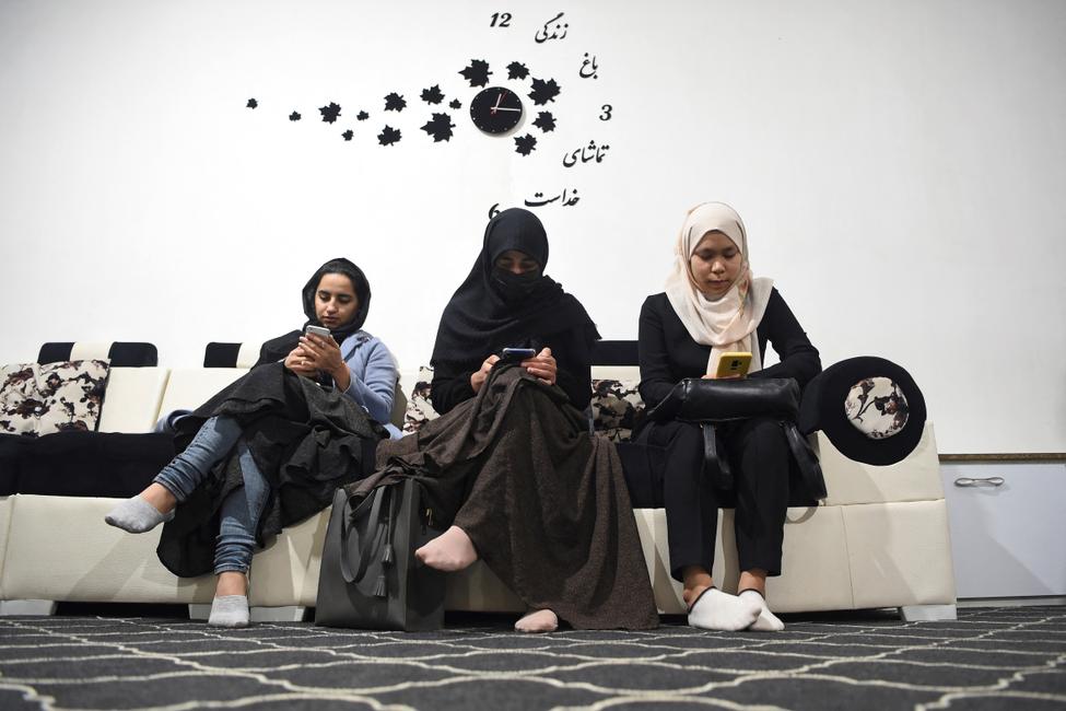Des étudiantes consultent leurs smartphones dans un bureau de change à Herat, en Afghanistan.