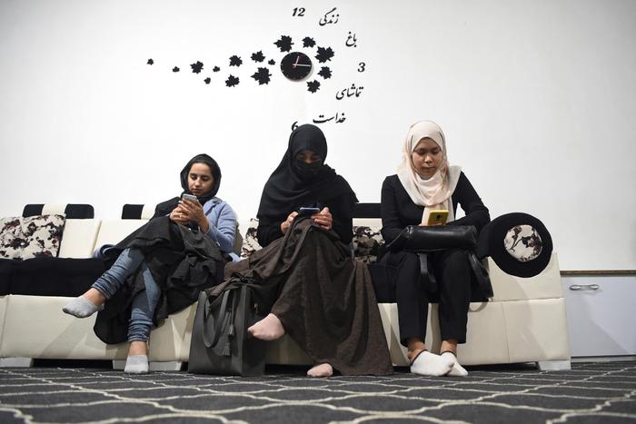 Des étudiantes consultent leurs smartphones dans un bureau de change à Herat, en Afghanistan.