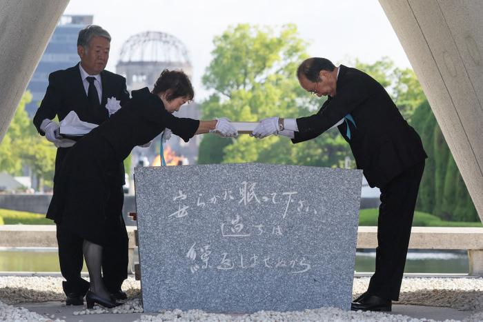 Le maire de la ville d'Hiroshima, Kazumi Matsui, et un représentant des familles endeuillées déposent une liste des victimes de la bombe atomique sur le cénotaphe lors de la cérémonie commémorative annuelle au parc du Mémorial de la Paix d'Hiroshima, le 6 août 2025, pour marquer les 80 ans de la première attaque à la bombe atomique au monde.