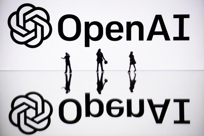 Cette photographie d'illustration montre des figurines à côté d'un écran affichant le logo d'OpenAI, l'entreprise américaine spécialisée dans l'intelligence artificielle et à l'origine de ChatGPT. 