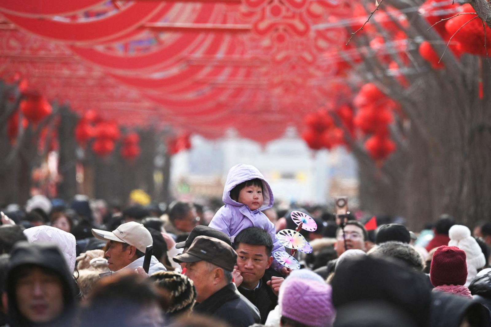 Un homme porte un enfant au-dessus de la foule lors d'une foire dans un temple, le deuxième jour du Nouvel An lunaire du Serpent à Pékin, le 30 janvier 2025.