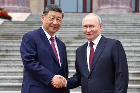 Sur cette photo de groupe diffusée par l'agence de presse russe Sputnik, le président russe Vladimir Poutine et le président chinois Xi Jinping se serrent la main lors d'une cérémonie de bienvenue au Palais de l'Assemblée du Peuple à Pékin, le 20 mai 2026.