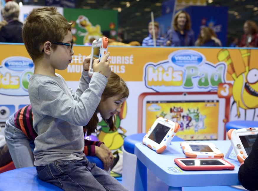 Des enfants jouent avec des tablettes numériques, lors du salon « Kidexpo » au parc des expositions de la Porte de Versailles à Paris.
