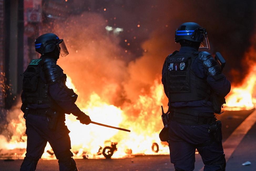 Des policiers se tiennent devant un incendie rue du Faubourg du Temple, tandis que des affrontements éclatent place de la République à la suite d'une manifestation non autorisée, dans le centre de Paris, le 18 octobre 2026, au lendemain des manifestations nationales contre le coût élevé de la vie.