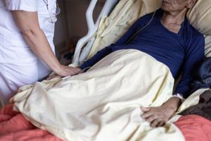 Une infirmière tient la main d'un patient pendant qu'elle le soigne dans l'unité de soins palliatifs de l'hôpital Paul-Brousse AP-HP de Villejuif.