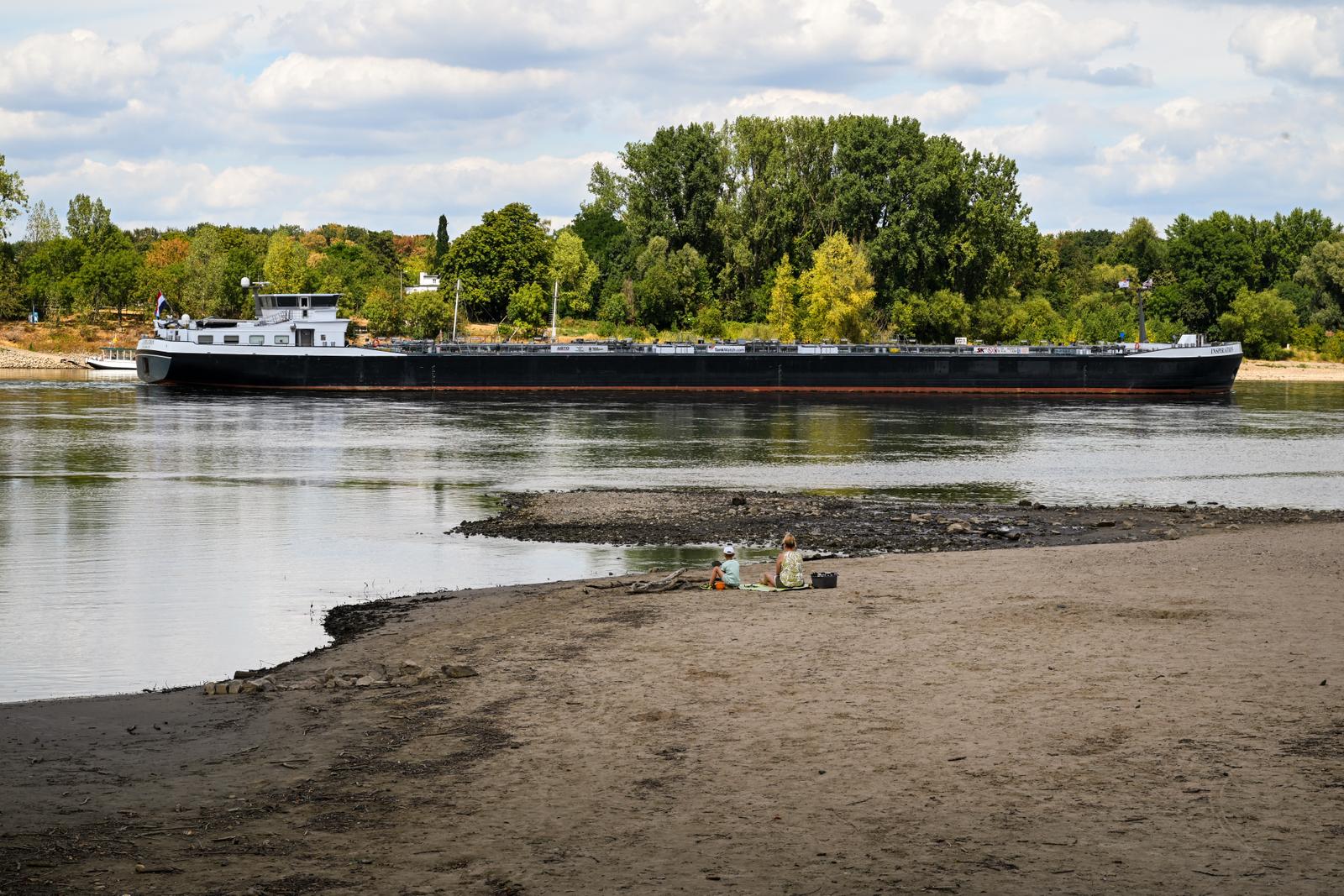 Un navire longe le lit partiellement asséché du Rhin, à hauteur du parc énergétique et chimique Shell Rheinland-Nord, à Godorf, près de Cologne, dans l’ouest de l’Allemagne, le 7 août 2026, après une période de chaleur exceptionnelle. La production industrielle et les exportations allemandes ont légèrement progressé en juin, a indiqué vendredi l’Office fédéral de la statistique, mais les analystes mettent en garde contre les risques liés à l’assèchement des cours d’eau et à la guerre au Moyen-Orient. (Image d'illustration)