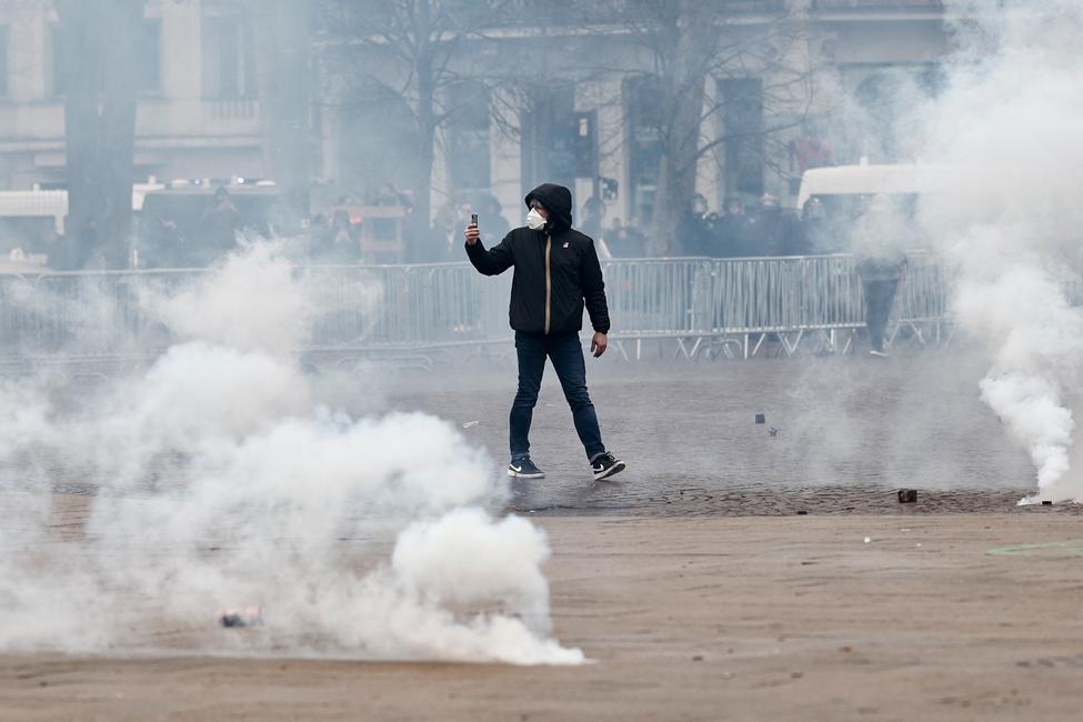 Un homme filme avec son smartphone, au milieu des gaz lacrymogènes tirés par les forces anti-émeutes, lors d'une manifestation à Lille.
