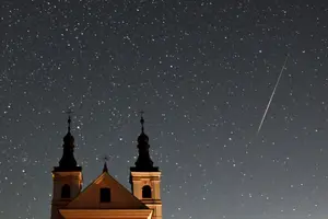 Cette photo à longue exposition montre un météore traversant le ciel nocturne au-dessus du monastère du village de Wigry, en Pologne, lors de la pluie d'étoiles filantes annuelle des Perséides, tôt le 12 août 2024.