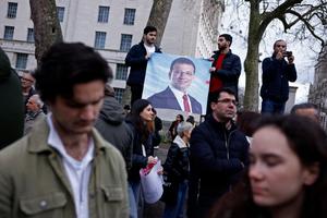 Des manifestants brandissent des pancartes et des drapeaux alors qu'ils participent à un rassemblement de soutien au maire d'Istanbul arrêté, dans le centre de Londres, le 22 mars 2025.